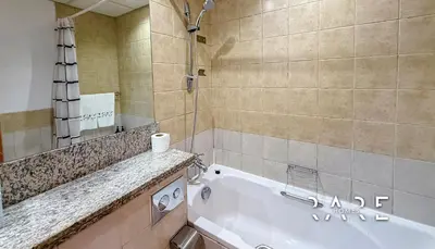 a bathroom with a bath tub and a sink at Rare Holiday Homes - Near Metro Station - Greens - Al Arta - R215 in Dubai