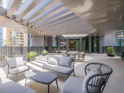 a patio with chairs and tables on a building at TRPS - Ahad Residences, Business Bay - 1BR Luxurious Apartment - Massive Balcony with Pool View in Dubai
