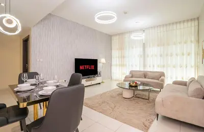 a living room with a television and a table and chairs at Granduer 1 BR in Windsor Manor Canal Front Living With Burj Views in Dubai