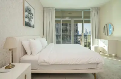 a bedroom with a white bed and a large window at Granduer 1 BR in Windsor Manor Canal Front Living With Burj Views in Dubai