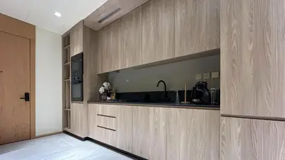 a kitchen with wooden cabinets and a sink at Bespoke Holiday Homes - Stylish 1BR Penthouse in The Autograph in Dubai