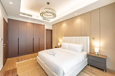 a bedroom with a large white bed and wooden cabinets at Contemporary 1BR Prime Location with Parking in Dubai
