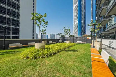 a park in the middle of a city with tall buildings at Contemporary 1BR Prime Location with Parking in Dubai