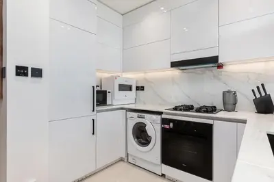 a white kitchen with a washing machine in it at Celestial View 1BR apartment in JVC in Dubai