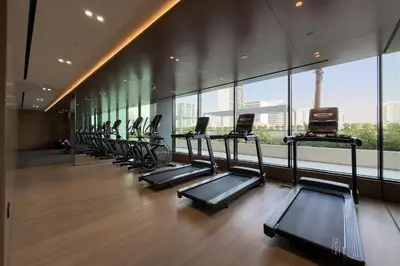 a row of treadmills in a gym with windows at Celestial View 1BR apartment in JVC in Dubai