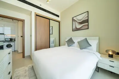 a bedroom with a large white bed and a kitchen at Modern JVC Apartment Views of Marina Skylines in Dubai