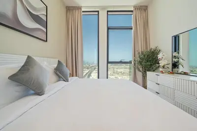 a bedroom with a white bed and a large window at Modern JVC Apartment Views of Marina Skylines in Dubai
