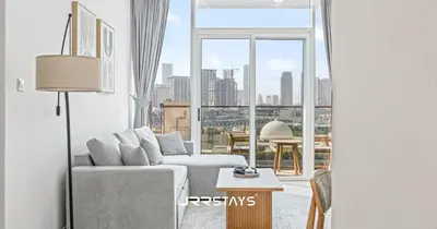 a living room with a couch and a large window at Elegant Luxury 1BR - Modern Design - JVC in Dubai