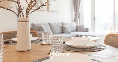 a dining room table with a white vase on it at Elegant Luxury 1BR - Modern Design - JVC in Dubai