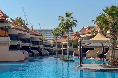 a swimming pool with palm trees in a resort at Homely 1 Bedroom on Palm Jumeirah with private beach in Dubai