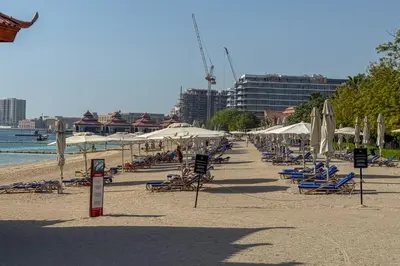 a beach with lounge chairs and umbrellas and the ocean at Homely 1 Bedroom on Palm Jumeirah with private beach in Dubai