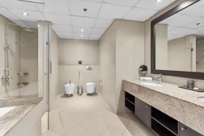 a bathroom with two sinks and a shower and a toilet at Homely 1 Bedroom on Palm Jumeirah with private beach in Dubai