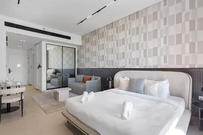 a bedroom with a large white bed and a living room at Stylish Studio with Jacuzzi in Business Bay in Dubai
