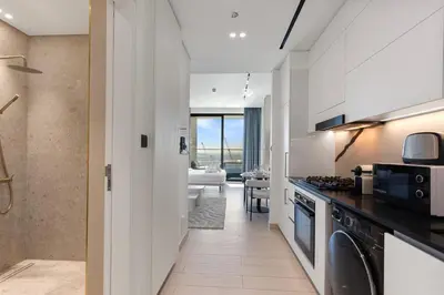 a kitchen with white cabinets and a living room at Stylish Studio with Jacuzzi in Business Bay in Dubai