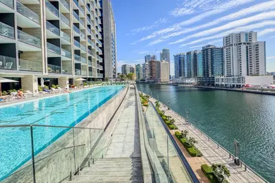 a swimming pool next to a river with buildings at Stylish Studio with Jacuzzi in Business Bay in Dubai
