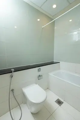 a white bathroom with a toilet and a bath tub at Marina Mirage in Dubai