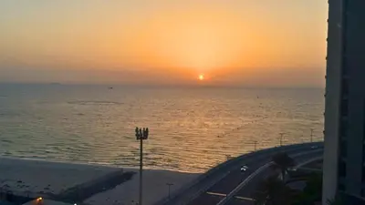 a view of the ocean with the sun setting over the water at Luxe Dubai Marina Apartment 5242 Building 2bhk in Dubai