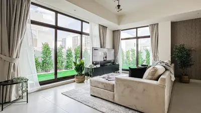 a living room with a couch and a tv and windows at Trophy-Lux Villa w Big Garden & BBQ Grill in Dubai