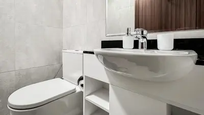 a white bathroom with a toilet and a sink at Trophy-Lux Villa w Big Garden & BBQ Grill in Dubai