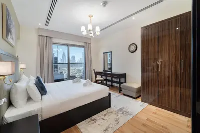 a bedroom with a bed and a desk and a window at 1BR with Balcony View, Gym, Pool & Kids Play Area in Dubai