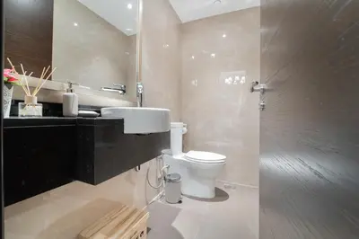 a bathroom with a toilet and a sink and a mirror at 1BR with Balcony View, Gym, Pool & Kids Play Area in Dubai