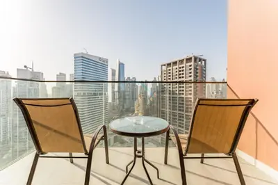 a table and two chairs on a balcony with a view at Luxury Studio Steps from Dubai Canal and Minutes to Burj Khalifa, Peninsula Five - 3, Business Bay By Deluxe Holiday Homes in Dubai