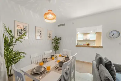 a dining room with a white table and chairs at FIRST CLASS 2BR Elegant Urban Retreat in Dubai