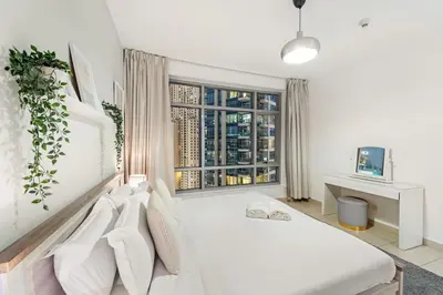 a white bedroom with a bed and a window at FIRST CLASS 2BR Elegant Urban Retreat in Dubai