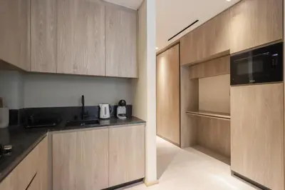 a kitchen with wooden cabinets and black counter tops at Livbnb - Stylish Studio in JVC, Near Parks and Shops in Dubai