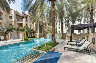 a swimming pool with palm trees next to a building at Cozy 1BR Apart Downtown Burj Khalifa and Dubai Mall in Dubai