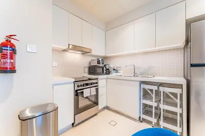 a kitchen with white cabinets and a refrigerator at High-Rise 1BR with Stunning Creek Views,Near to Dubai Creek Tower Viewpoint, Harbour Gate Tower 2, Dubai Creek Harbour by Deluxe Holiday Homes in Dubai