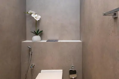 a bathroom with a toilet and a vase with flowers on a shelf at 2BR by Sea, 15min to Dubai Mall in Dubai