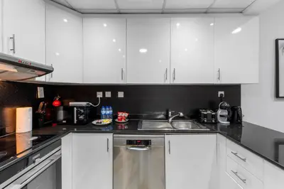 a kitchen with white cabinets and a sink at Stylish 2BR in Elite Tower with Bluewaters View and JBR in Dubai