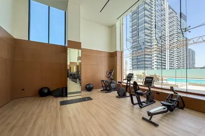 a gym with cardio equipment in a room with a large window at Stylish 1-Bedroom in Binghatti House JVC in Dubai