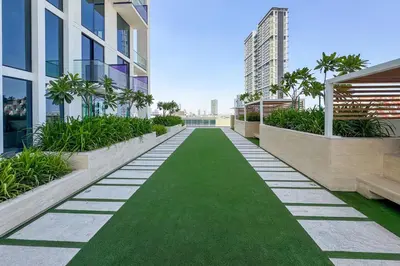a walkway with green grass in a building at Stylish 1-Bedroom in Binghatti House JVC in Dubai