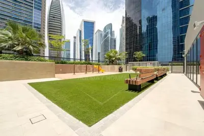 a park with benches and grass in a city at Canal Luxe Burj 1BR Sleeps 4 with Pool and Gym in Dubai