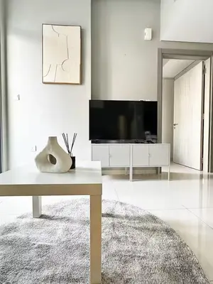 a living room with a table and a television at Canal Luxe Burj 1BR Sleeps 4 with Pool and Gym in Dubai