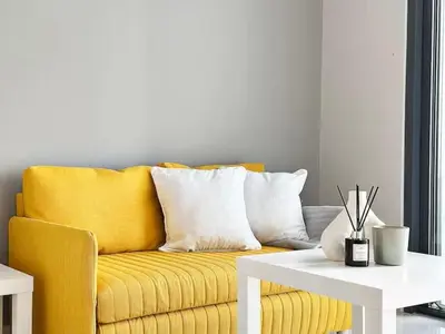 a yellow couch in a living room with a white table at Canal Luxe Burj 1BR Sleeps 4 with Pool and Gym in Dubai