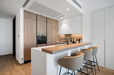 a kitchen with wooden cabinets and a counter with bar stools at The Marina Observatory-Jumeirah Living Marina Gate in Dubai
