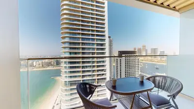 a balcony with a table and chairs and a large building at Grand Bleu 2 - Sophisticated Two Bed with Sea View in Dubai