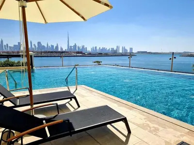 a swimming pool with two chairs and an umbrella at La Mer 1BR Ocean View 4 Pax in Dubai