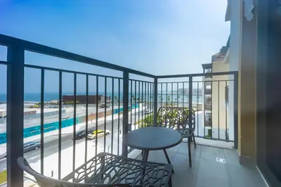 a balcony with a table and chairs and a view of the ocean at La Mer 1BR Ocean View 4 Pax in Dubai