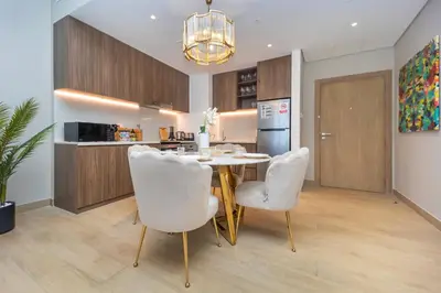 a kitchen and dining room with a table and white chairs at La Mer 1BR Ocean View 4 Pax in Dubai