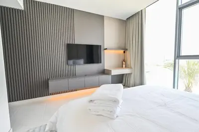 a bedroom with a bed with a tv on a wall at Chic 2BR Heart of District One in Dubai