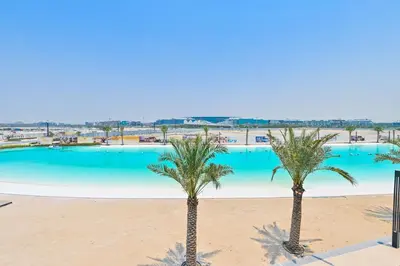 two palm trees in front of a swimming pool at Chic 2BR Heart of District One in Dubai