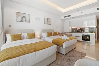 two beds in a white room with a kitchen at Luxurious New Studio! 2 Double Beds! Sleek Design & High-End Amenities in Dubai Downtown in Dubai