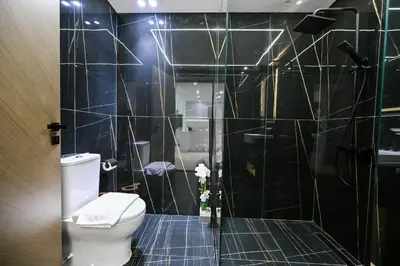 a black tiled bathroom with a toilet and a shower at Stunning 1 br modern luxury residence at JVC in Dubai