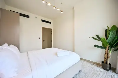 a bedroom with a white bed and a potted plant at Stunning 1 br modern luxury residence at JVC in Dubai