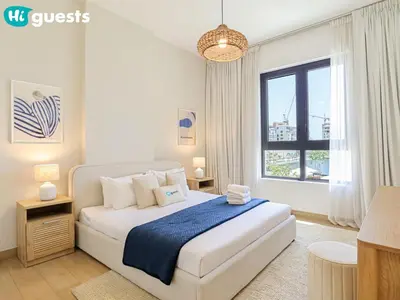 a white bedroom with a large bed and a window at HiGuests - Seaside Serenity 1 BR at Port De La Mer in Dubai
