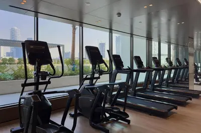 a row of exercise bikes in a gym with a large window at Stylish 1BR Apartment in Binghatti Onyx JVC in Dubai